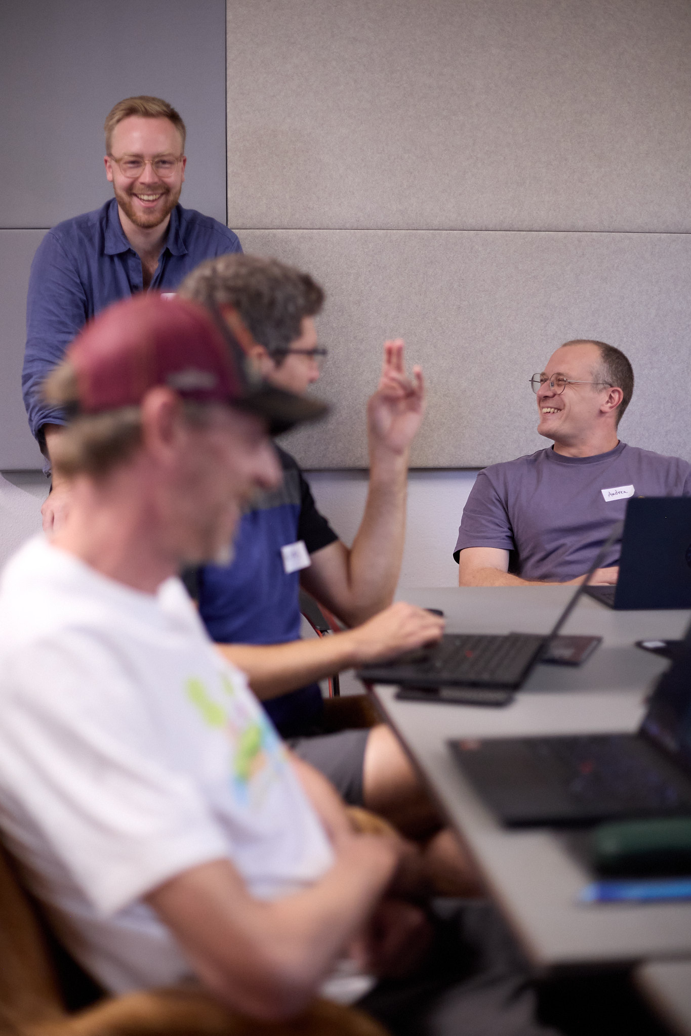 Participants around a table at the planqc workshop, laughing as one of them raises a hand to answer